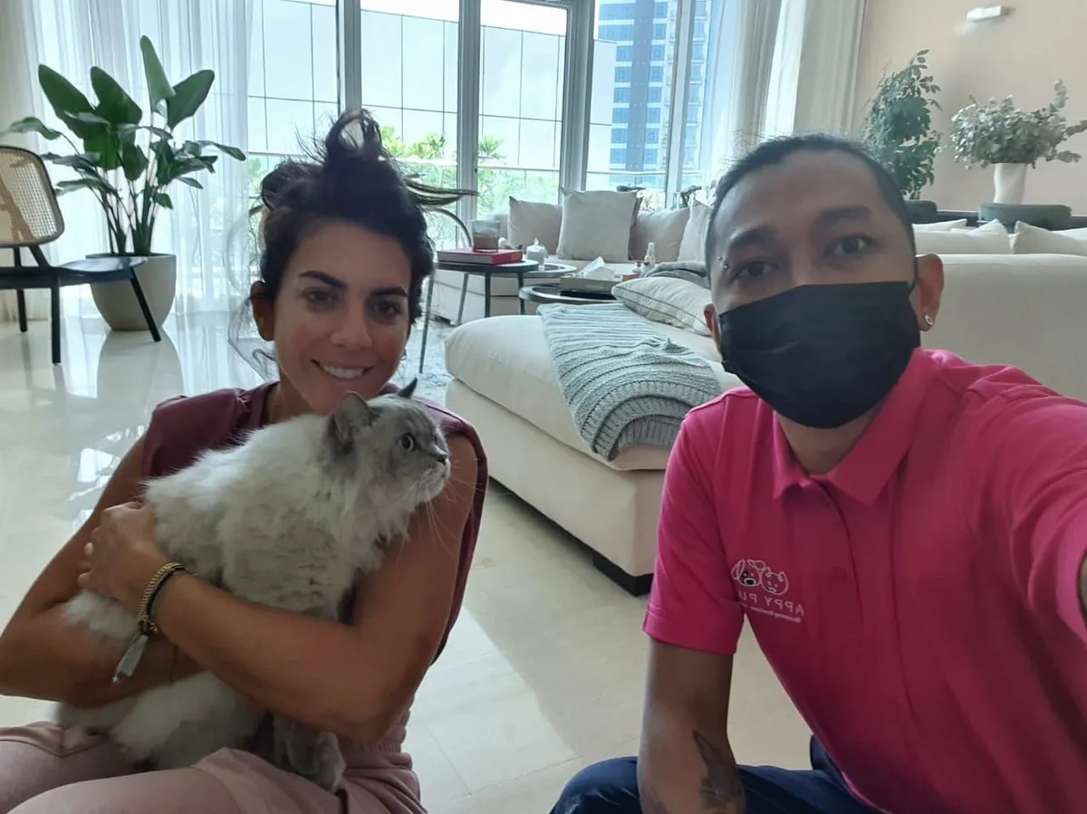 Groomer with a happy owner and her long-haired cat during a home visit in Dubai
